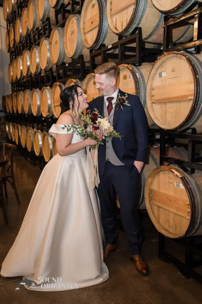 Newlyweds looking lovingly at each other with the barrels of wine at the background at Folino Estate Winery
