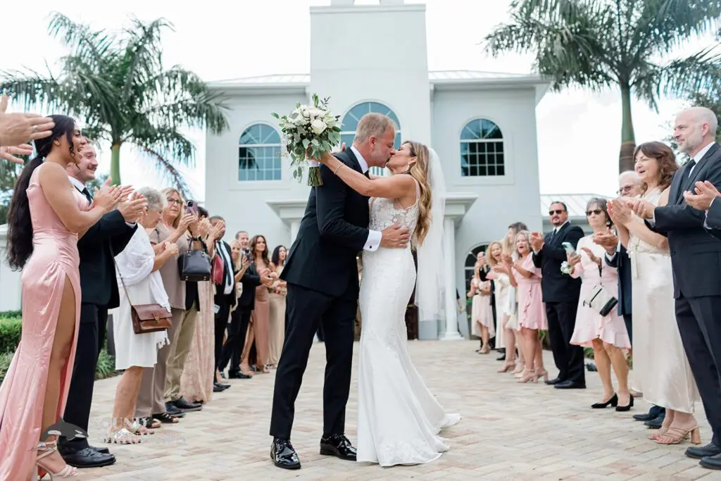 Newlyweds exit the Harborside Chapel Wedding and kiss in front of the cheering crowd