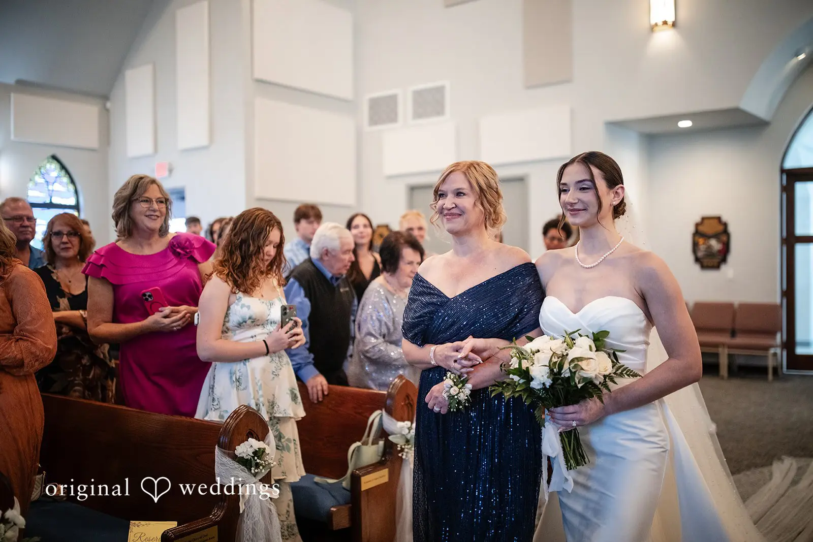 Bride walking arm-in-arm with companion, both smiling at Canterbury Hall Tampa Wedding