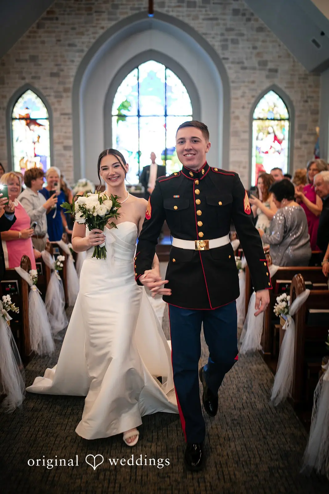 Newly married couple walking hand in hand out of the hall, smiling and celebrating