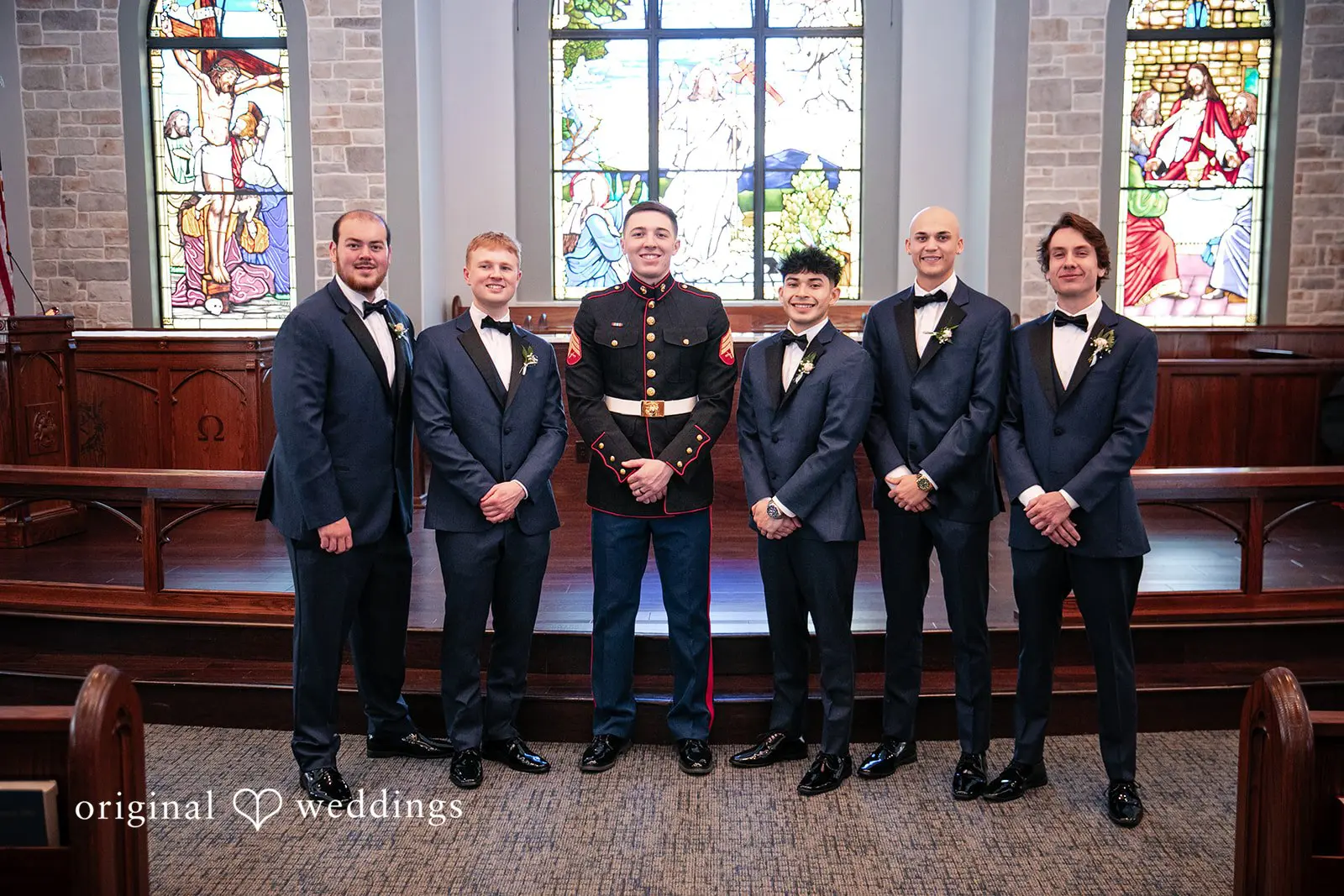 Groom in a suit standing with his groomsmen, all in formal attire and smiling together