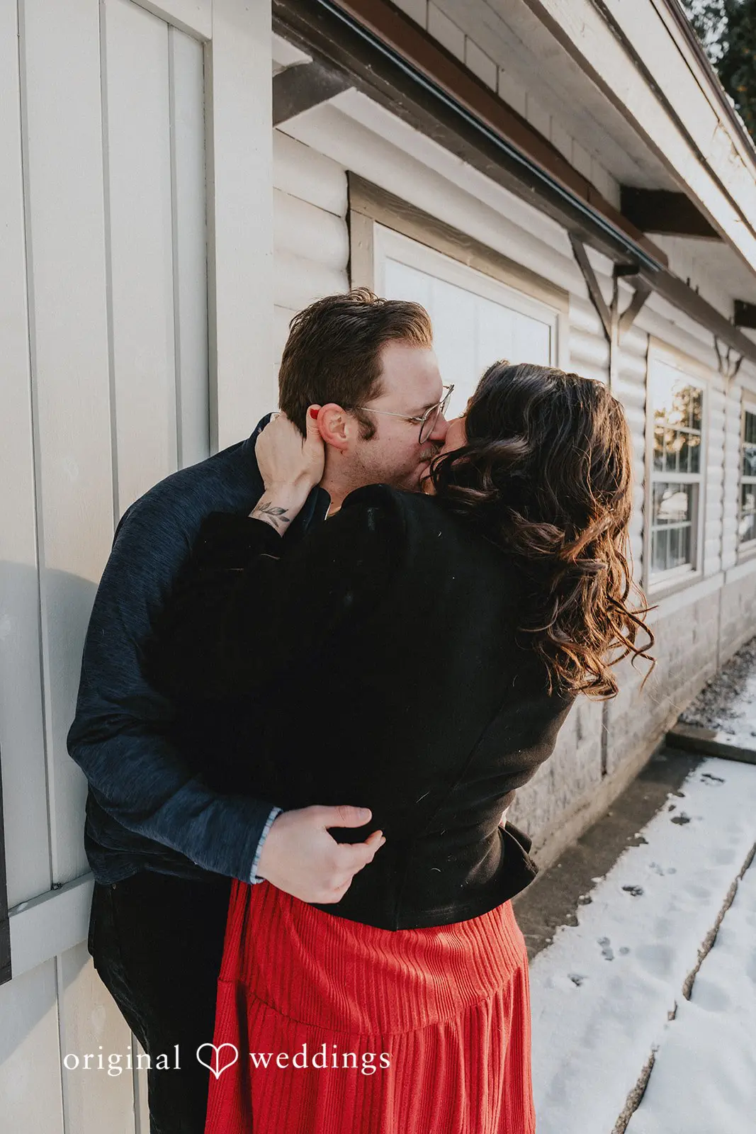 The couple shares a romantic kiss by the building