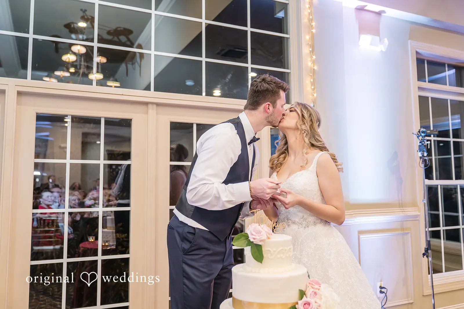 The bride and groom kiss after cutting their wedding cake