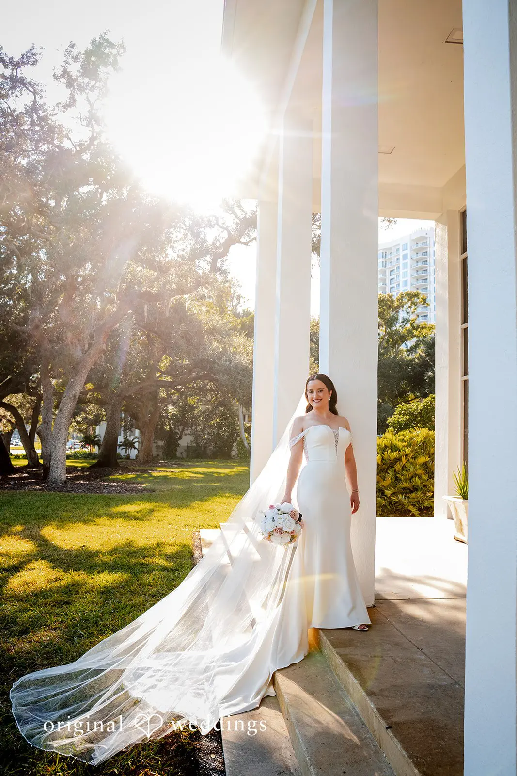 Bride standing in soft sunlight with her long veil flowing during portraits at Tampa Garden Club