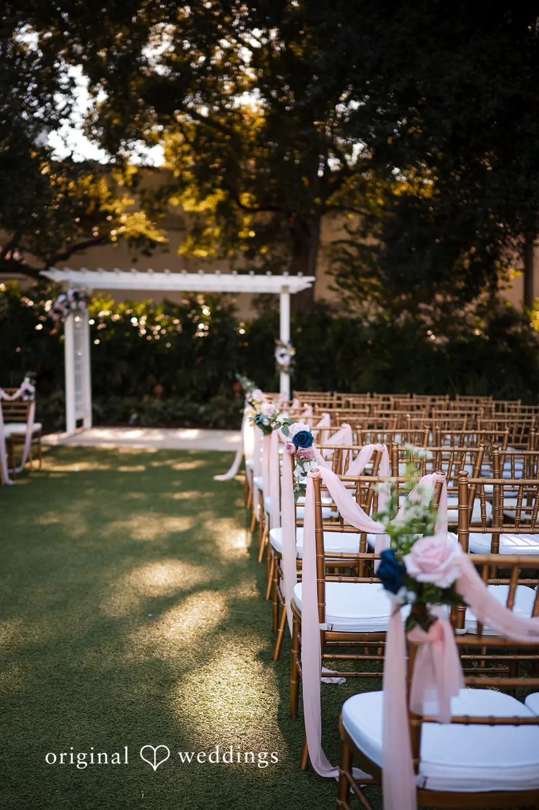 Outdoor ceremony aisle with white chairs and arbor at Tampa Garden Club garden
