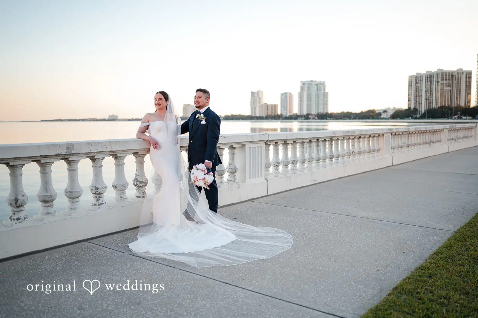 Bride and groom posing for portraits by the waterfront at Tampa Garden Club with views of the Tampa skyline