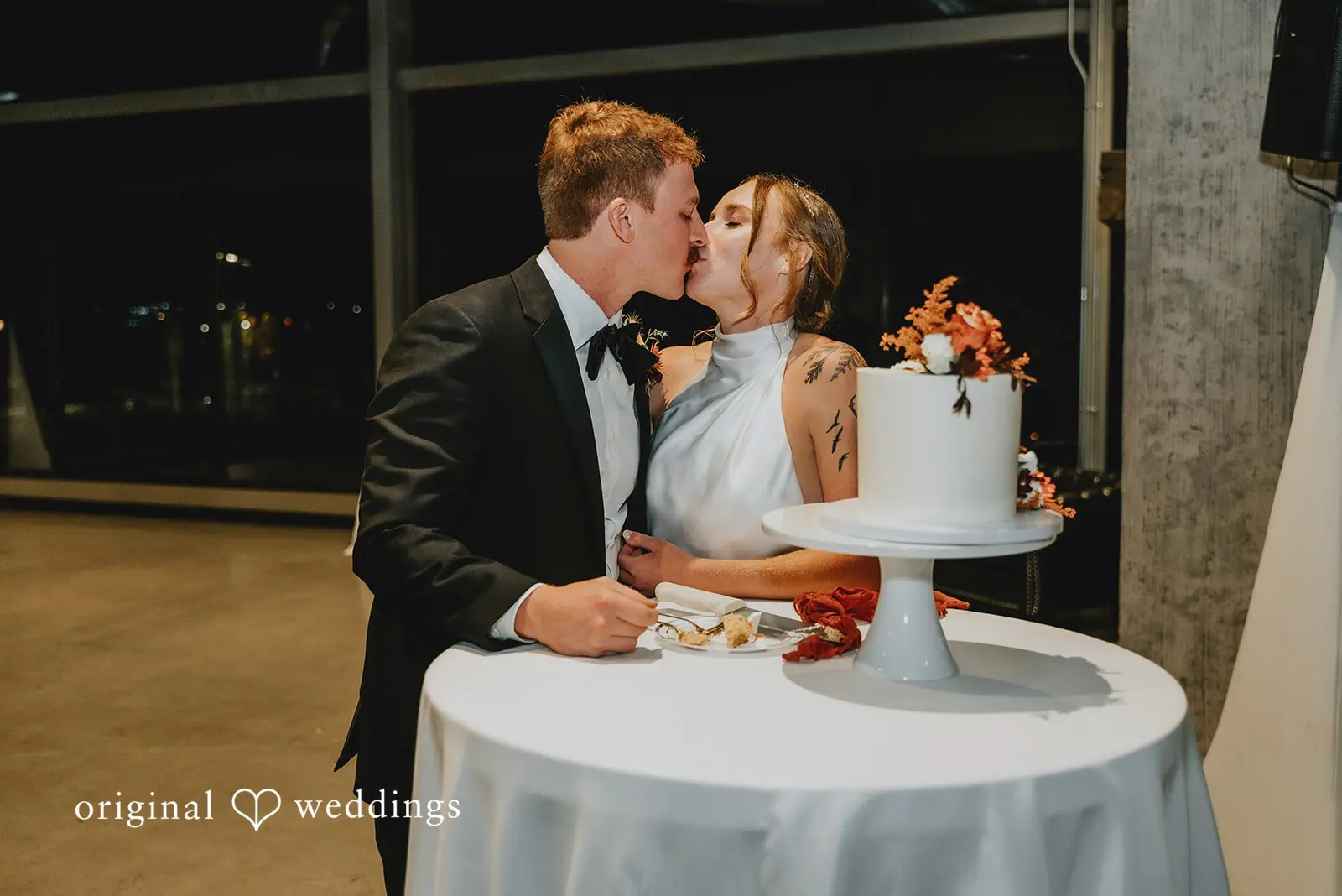 The couple kisses after cutting their wedding cake