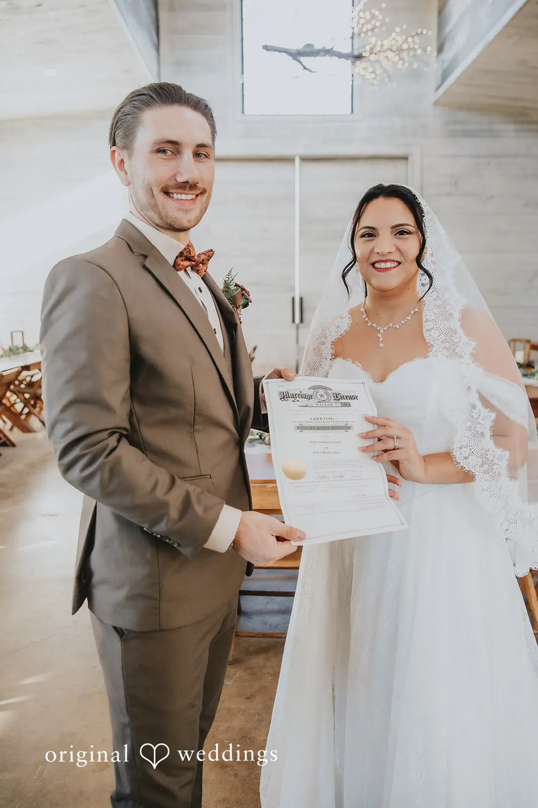A portrait of the bride and groom posing with their marriage certificate