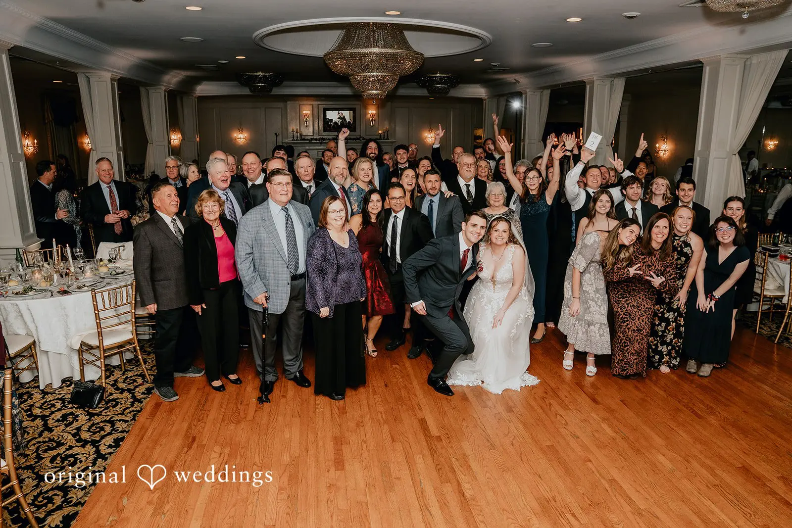 A portrait of the couple with their wedding party at their wedding reception