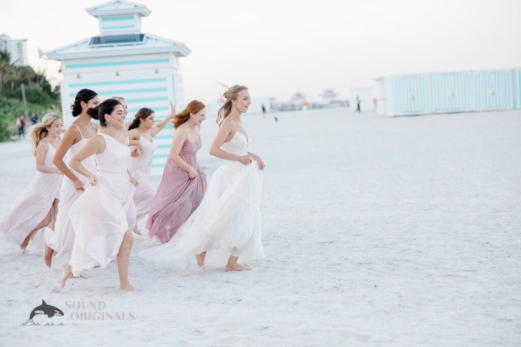 The bride and her bridesmaids running on the beach as part of their The Palms Hotel & Spa Wedding