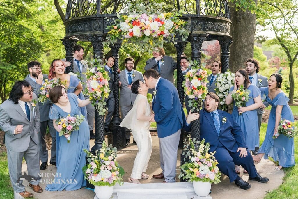 Kiss between the bride and groom and their bridal party looking on at Monte Bello Estate Wedding