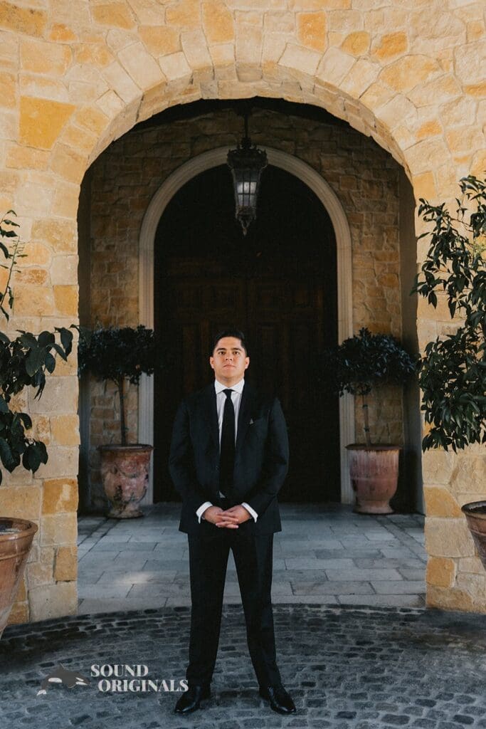 Elegant groom takes a shot in front of The Havens Country Club building