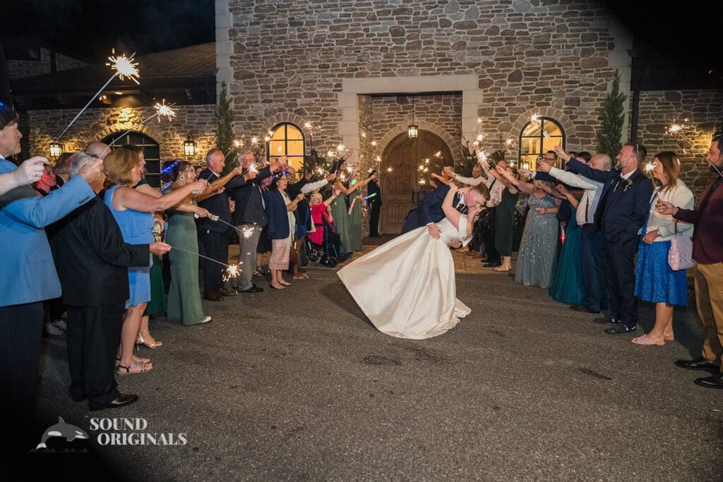 Bride and groom dip and kiss with guests holding sparklers up at Folino Estate Winery