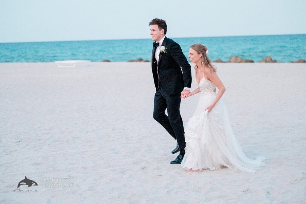 The bride and groom running on the beach as part of their The Palms Hotel & Spa Wedding celebration