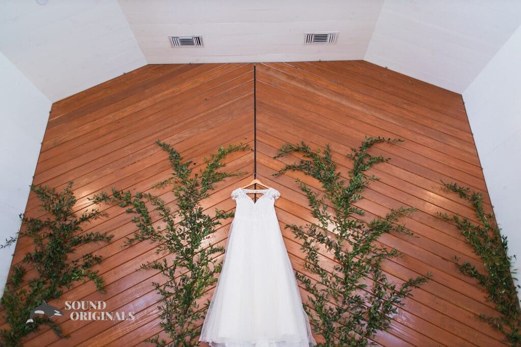 Sparkling white wedding gown hangs on Cliff House Dallas altar