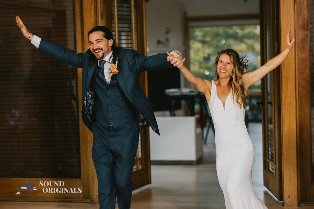 Happy husband and wife lift their hands in excitement over a successful Rembrandt Yard Wedding
