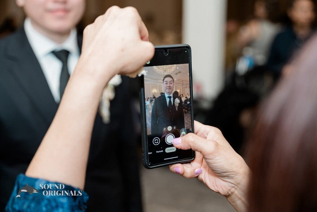 Guest taking a photo of the groom at The Abbington Distinctive Banquets Wedding