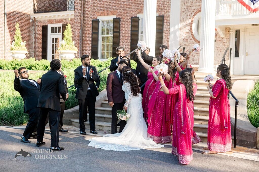 The bridal party posing while the bride and groom share a kiss at their Embassy Suites by Hilton Naperville Wedding