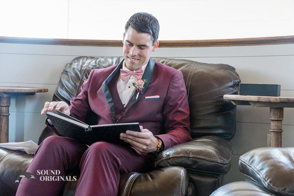 Handsome groom goes through the wedding book on The French Farmhouse couch
