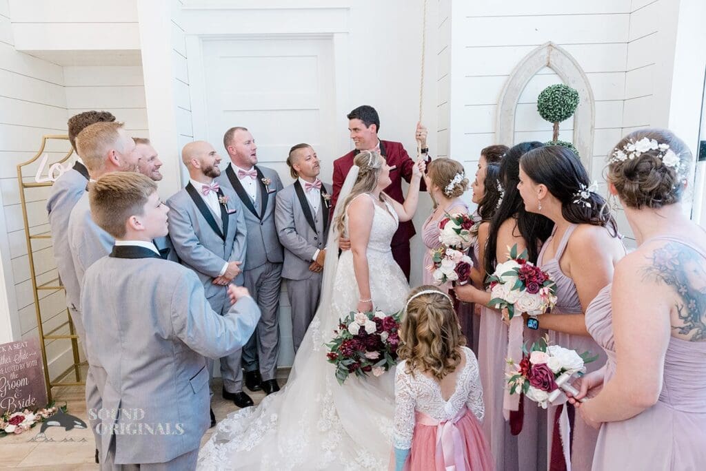 Husband and wife in a happy moment with bridal train and groom's men after The French Farmhouse Wedding