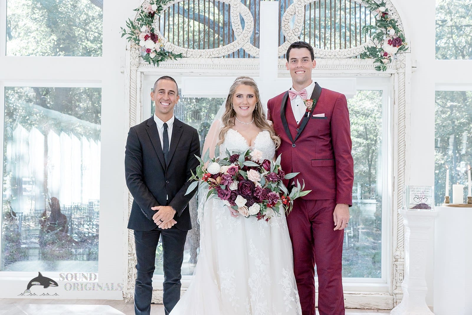 Charming husband and wife pose for a shot with wedding priest in The French Farmhouse Wedding