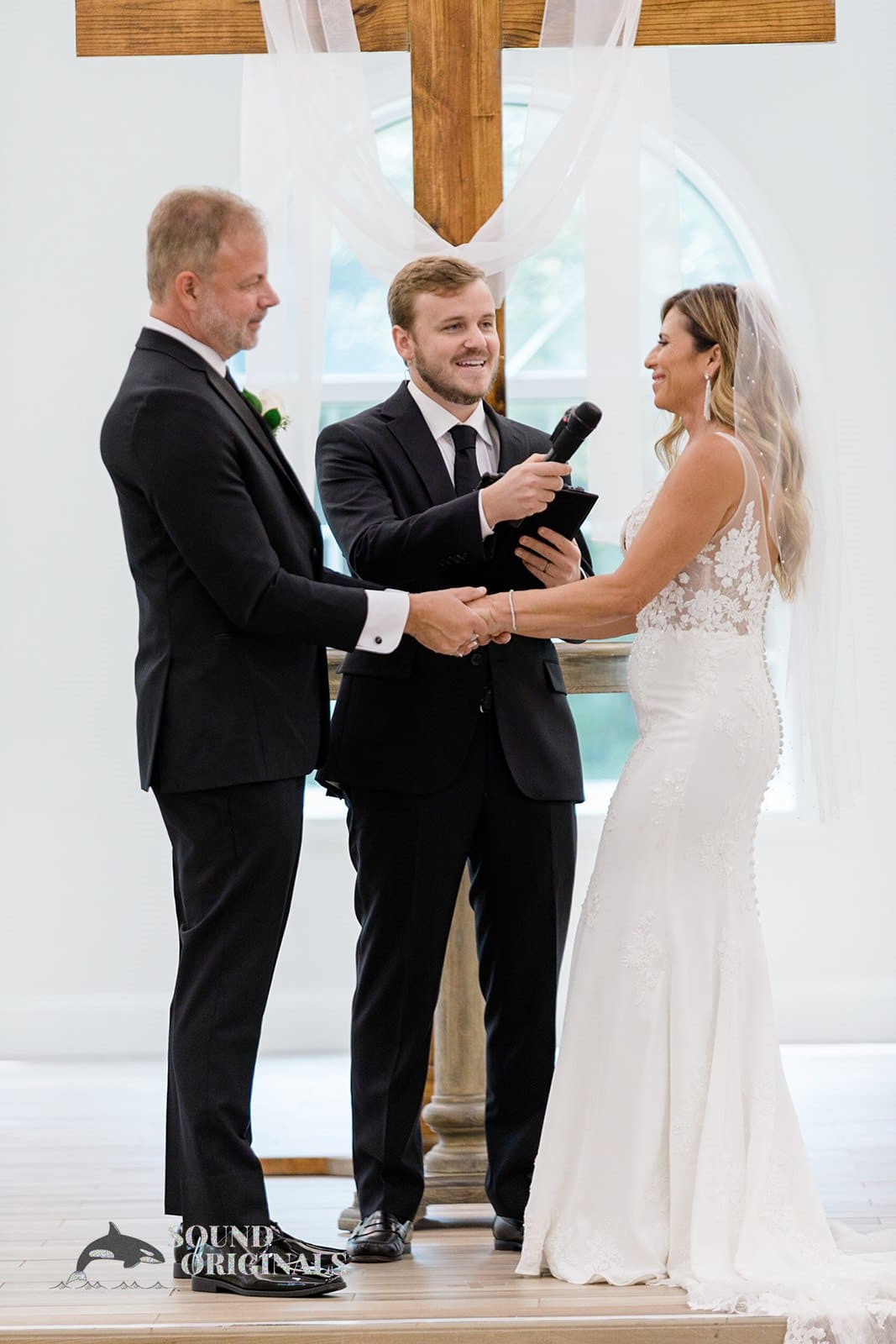 Bride and groom hold hands and gaze at each other during the Harborside Chapel Wedding