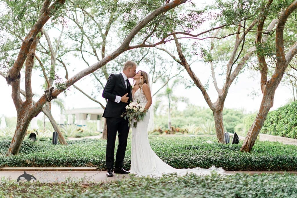 Harborside Chapel Wedding Newlyweds kiss beneath the trees after the Harborside Chapel Wedding