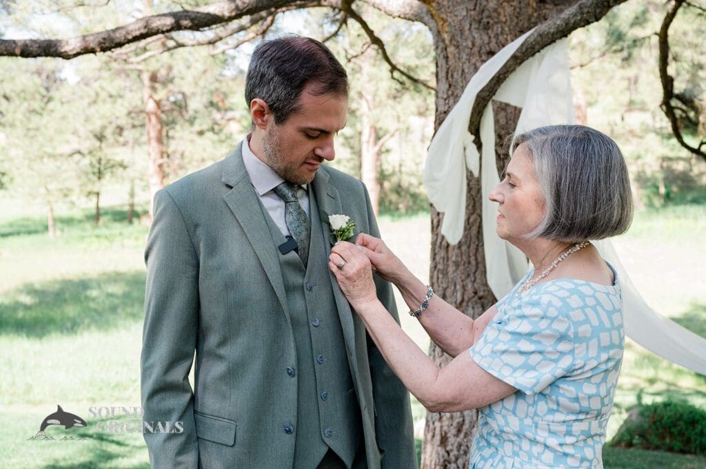 The groom getting his boutonniere added to his suit at The Red Farmhouse Bed & Breakfast Wedding