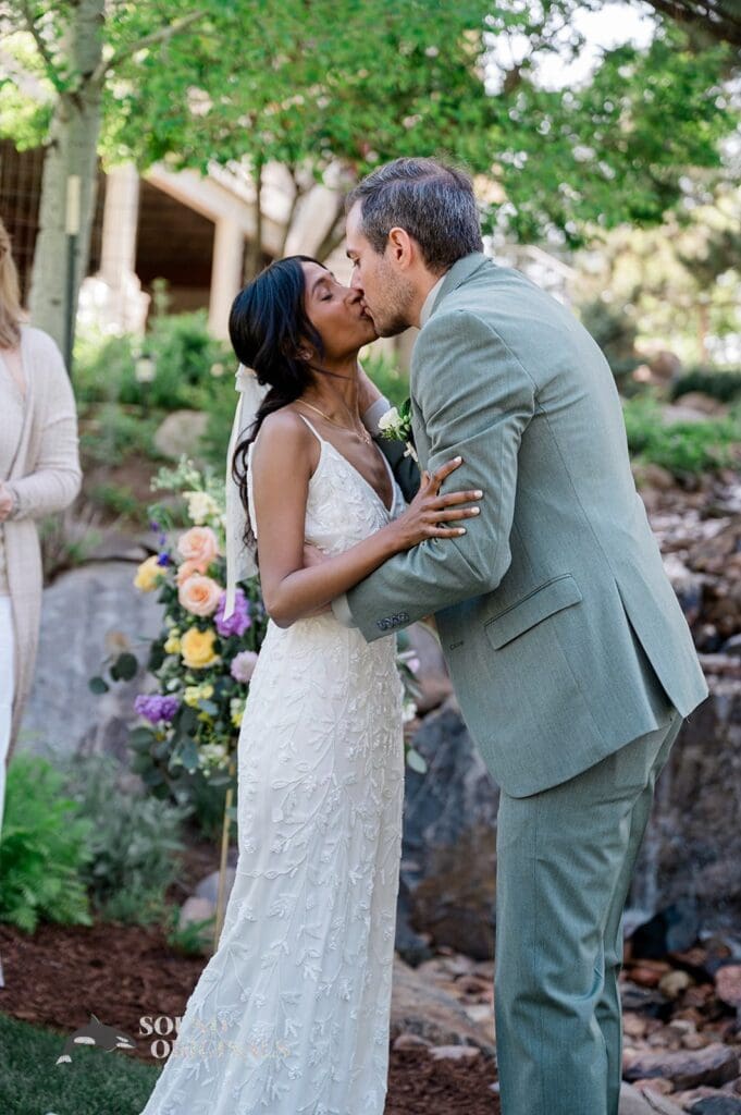 Bride and groom share a kiss at the altar of The Red Farmhouse Bed & Breakfast Wedding