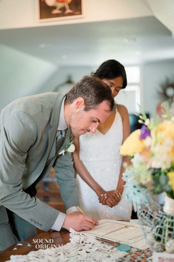 Groom signs the wedding certificate at The Red Farmhouse Bed & Breakfast Wedding