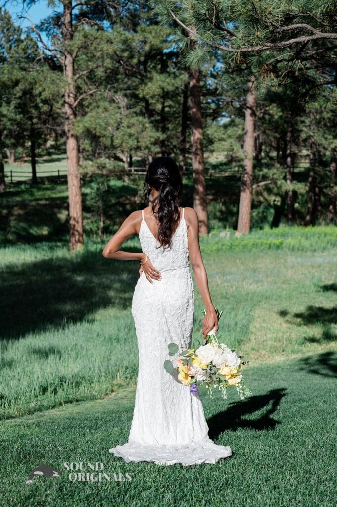 Portrait of the back of the bride with bouquet down at her side outside The Red Farmhouse Bed & Breakfast