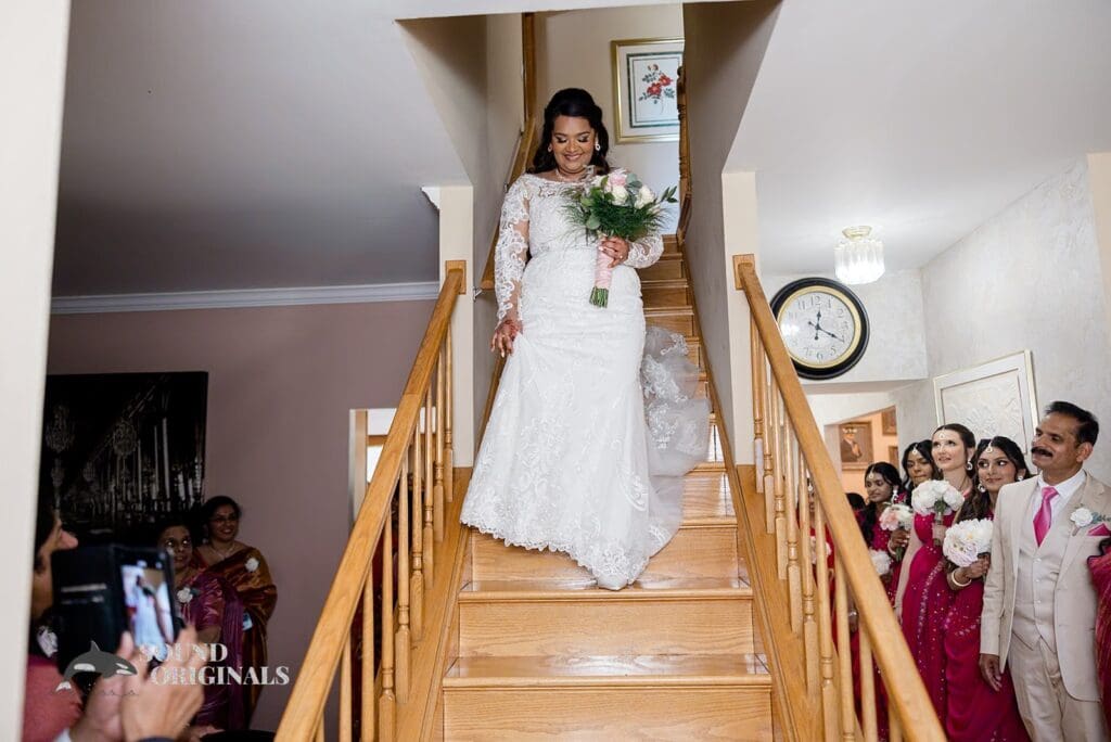 The bride coming down the stairs with bridesmaids and others looking on before her Embassy Suites by Hilton Naperville Wedding