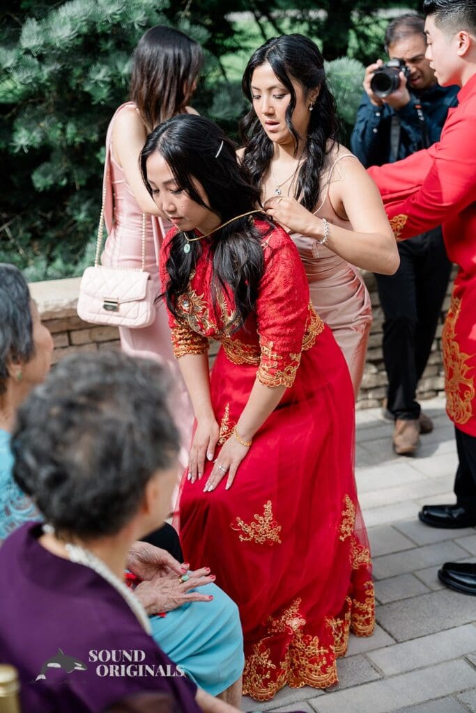 Bridesmaid putting necklace on the bride at The Abbington Distinctive Banquets Wedding