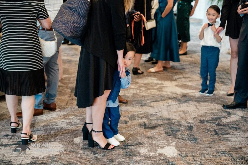 Little boy hiding between his mum's legs at The Abbington Distinctive Banquets Wedding