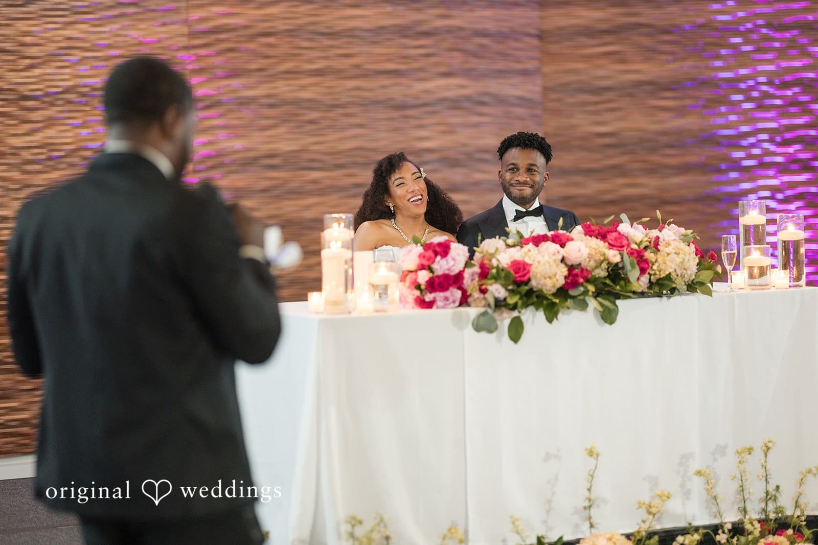 Ramon + Alexandra Bride and groom sit at wedding table as speaker addresses guests