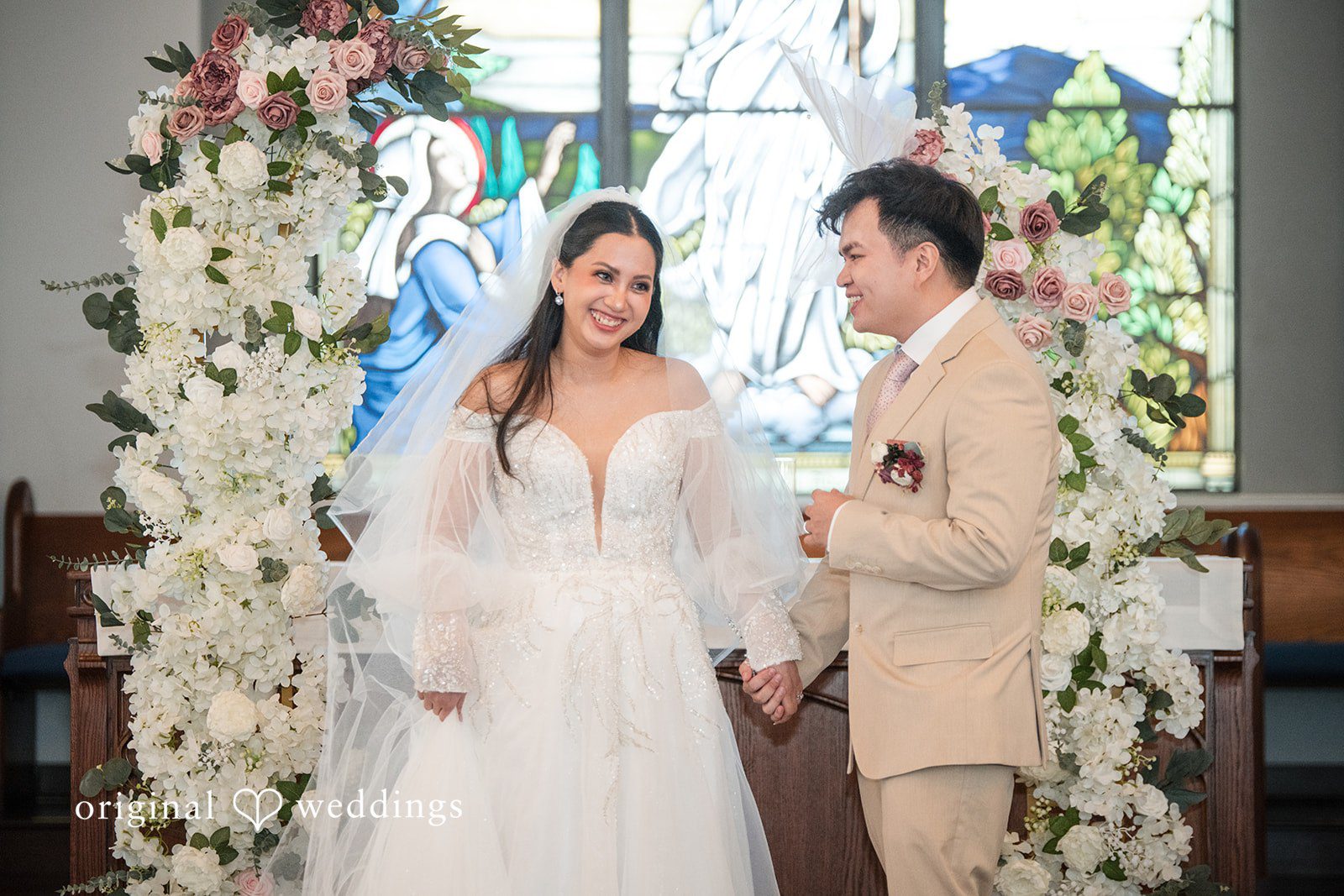 Andrea Edna + Canh Bride and groom in front of floral arch.