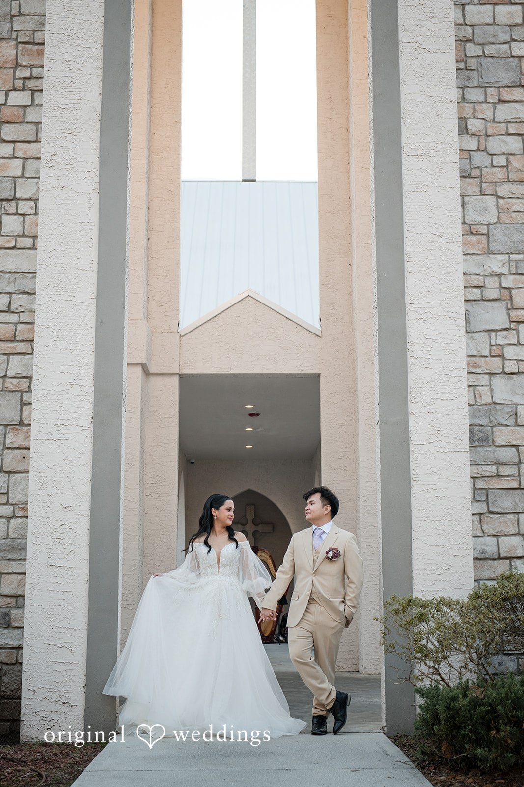 Andrea Edna + Canh Newlyweds embracing outside a building after a wedding.