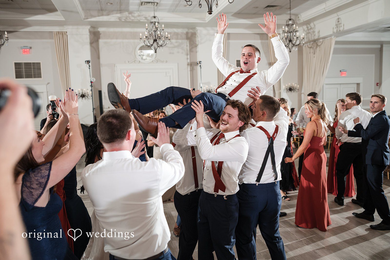 A fun portrait of the groomsmen lifting the groom up in excitement