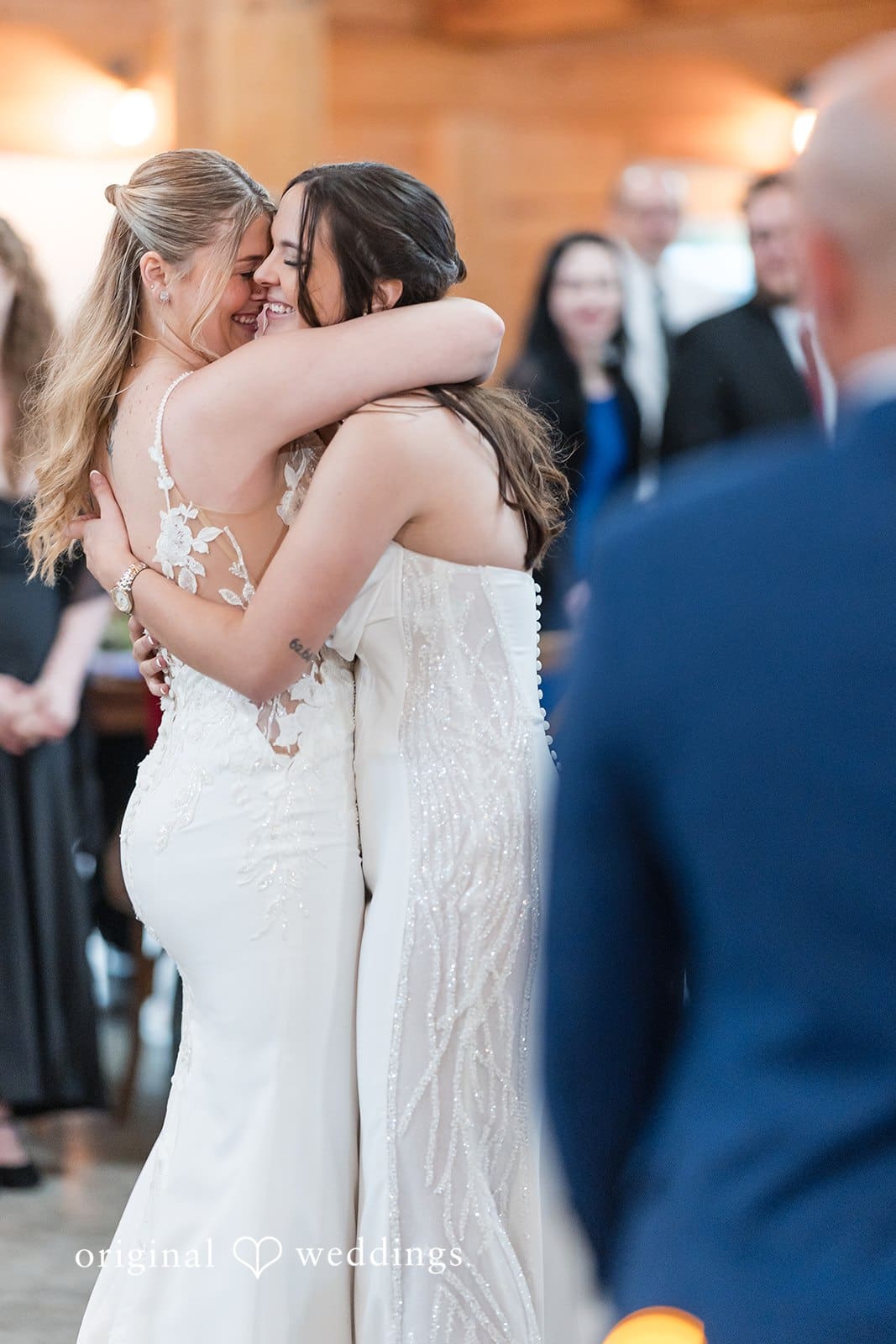 Bride couple embracing in wedding dresses during a ceremony.