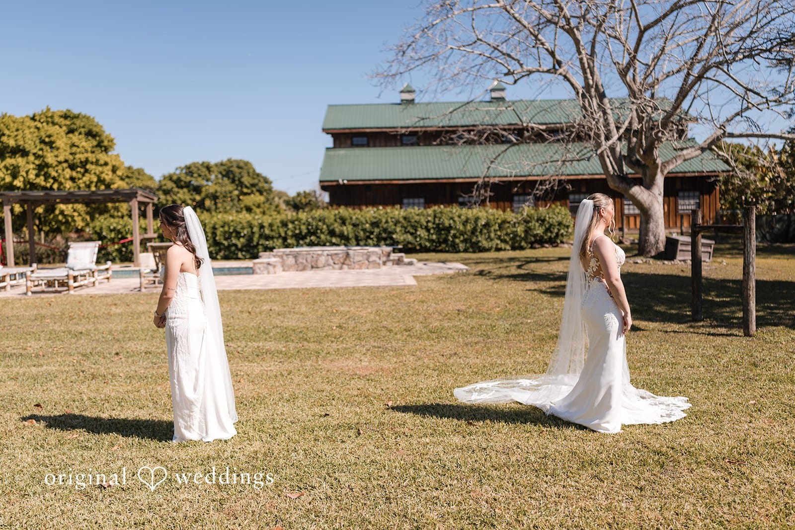 Two brides in white wedding gowns outdoors.
