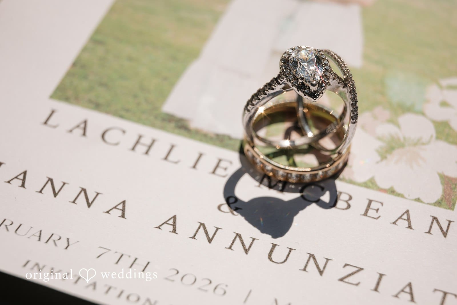 Wedding invitation suite with rings placed on top.