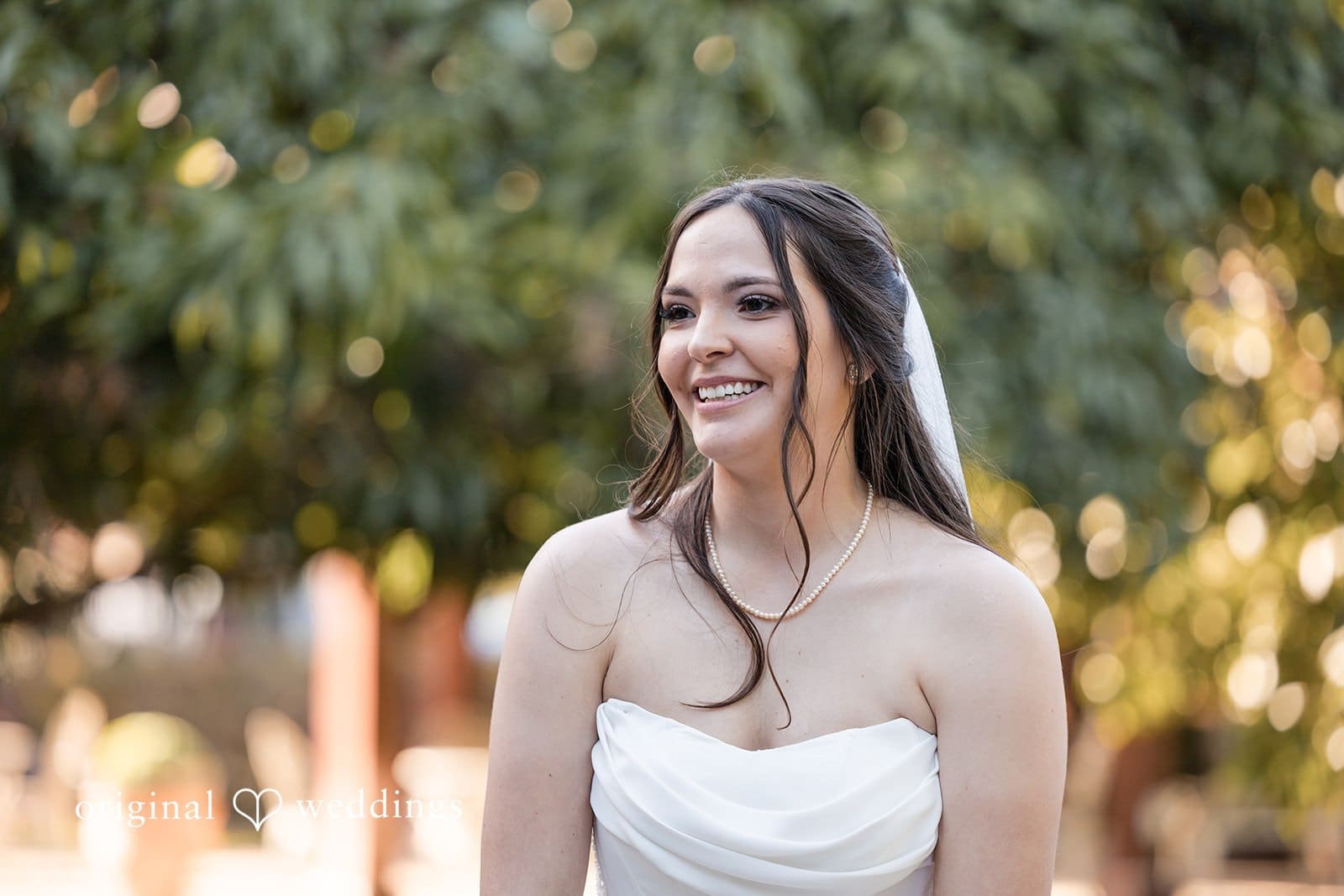 Bride standing outdoors with natural greenery background.