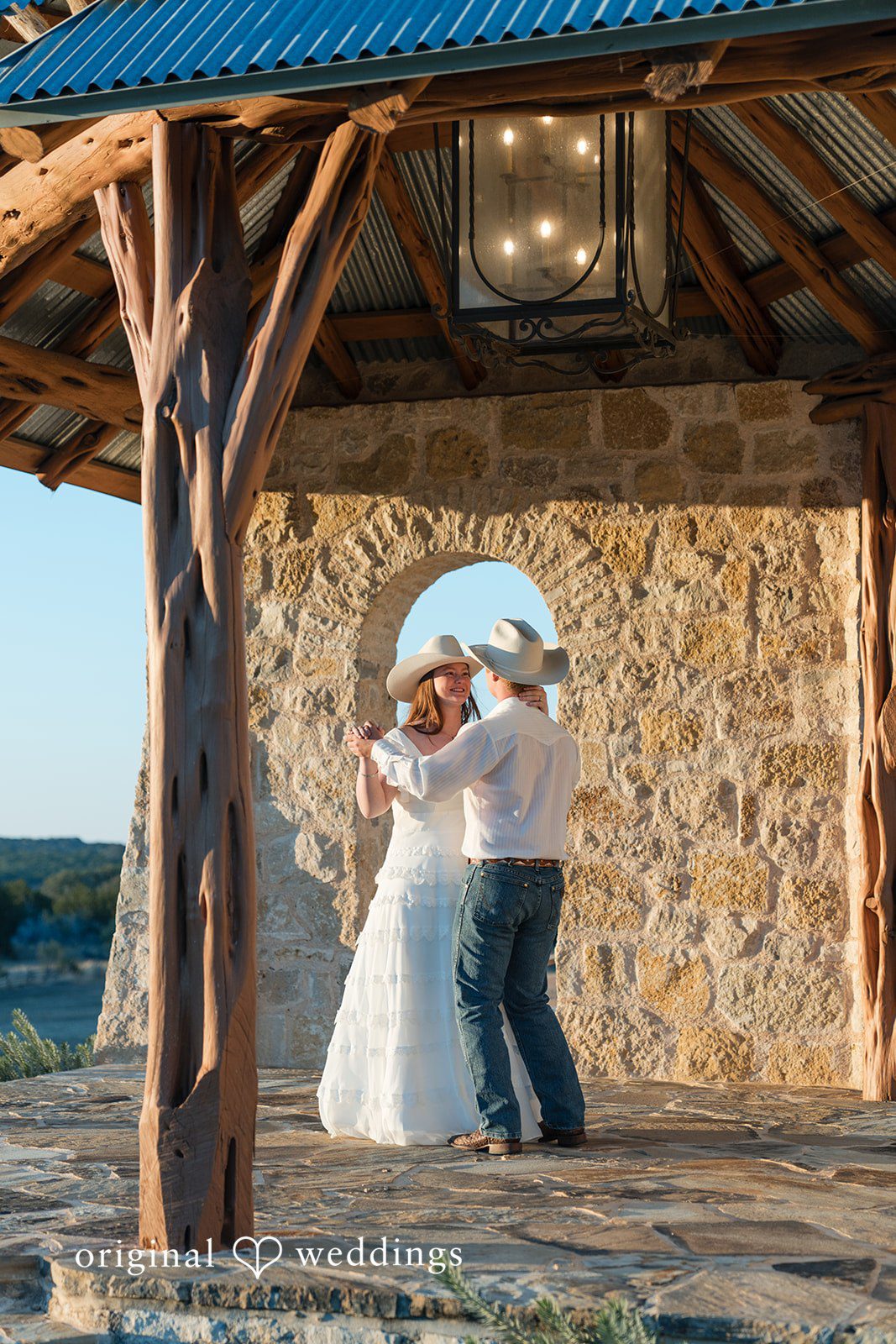 Under a rustic wooden shelter, they share a soft and loving moment.