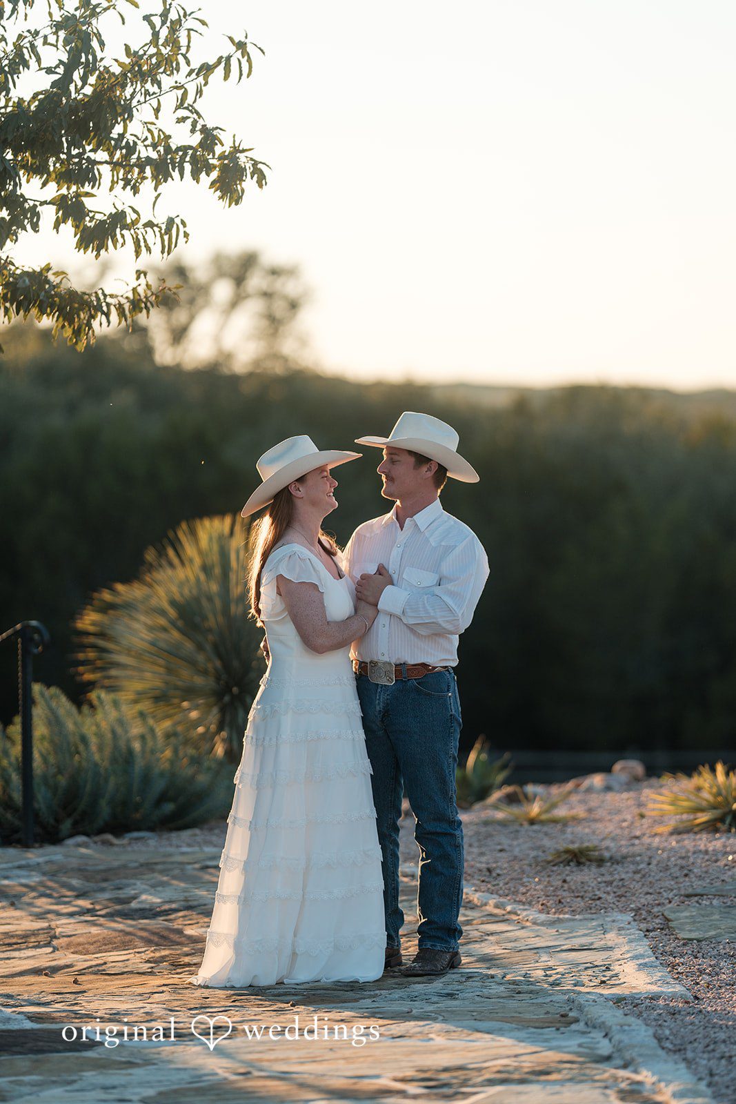 A romantic sunset moment as the couple gently holds hands in the open field.