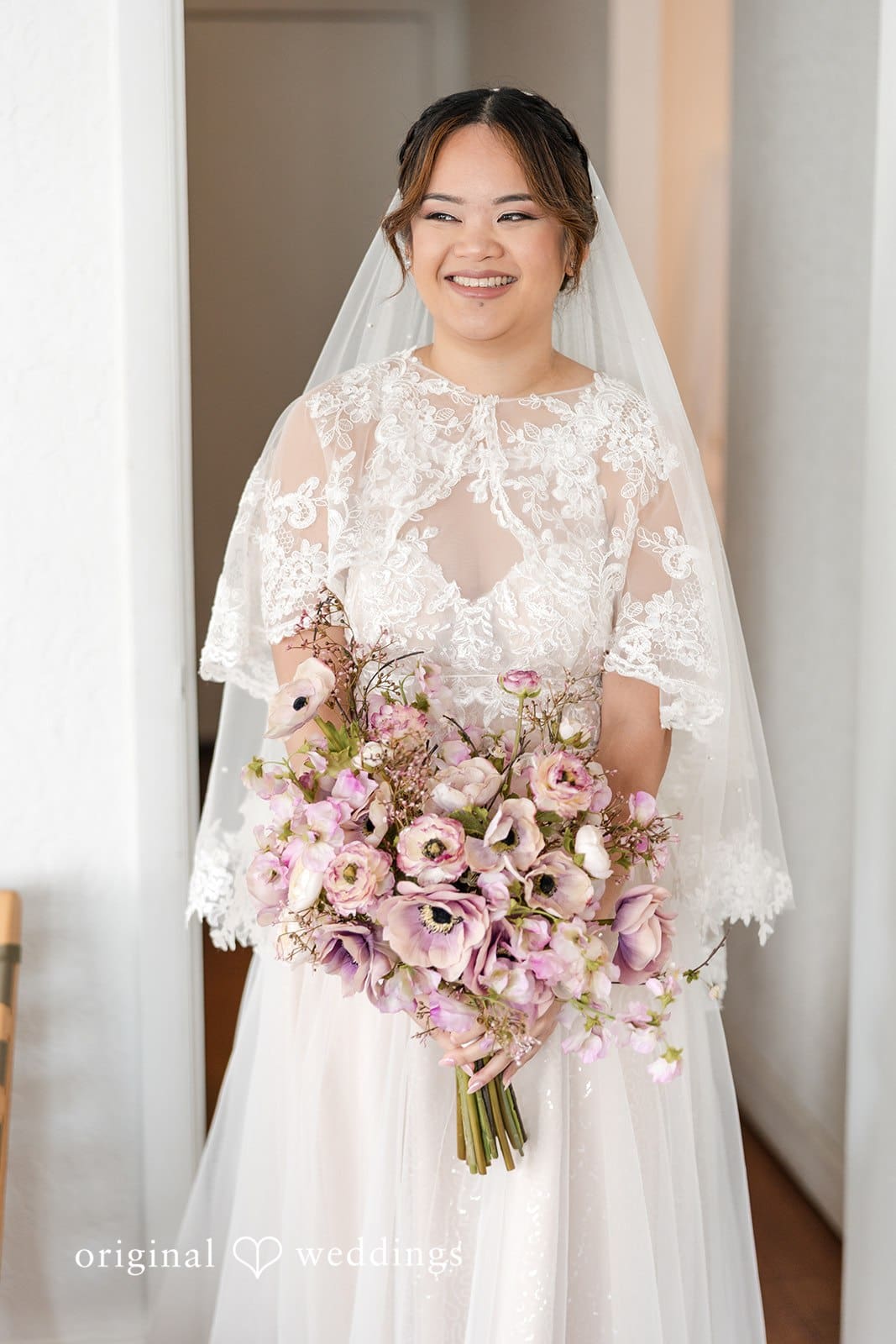 Bride smiling and holding a bouquet of mauve and pink flowers.