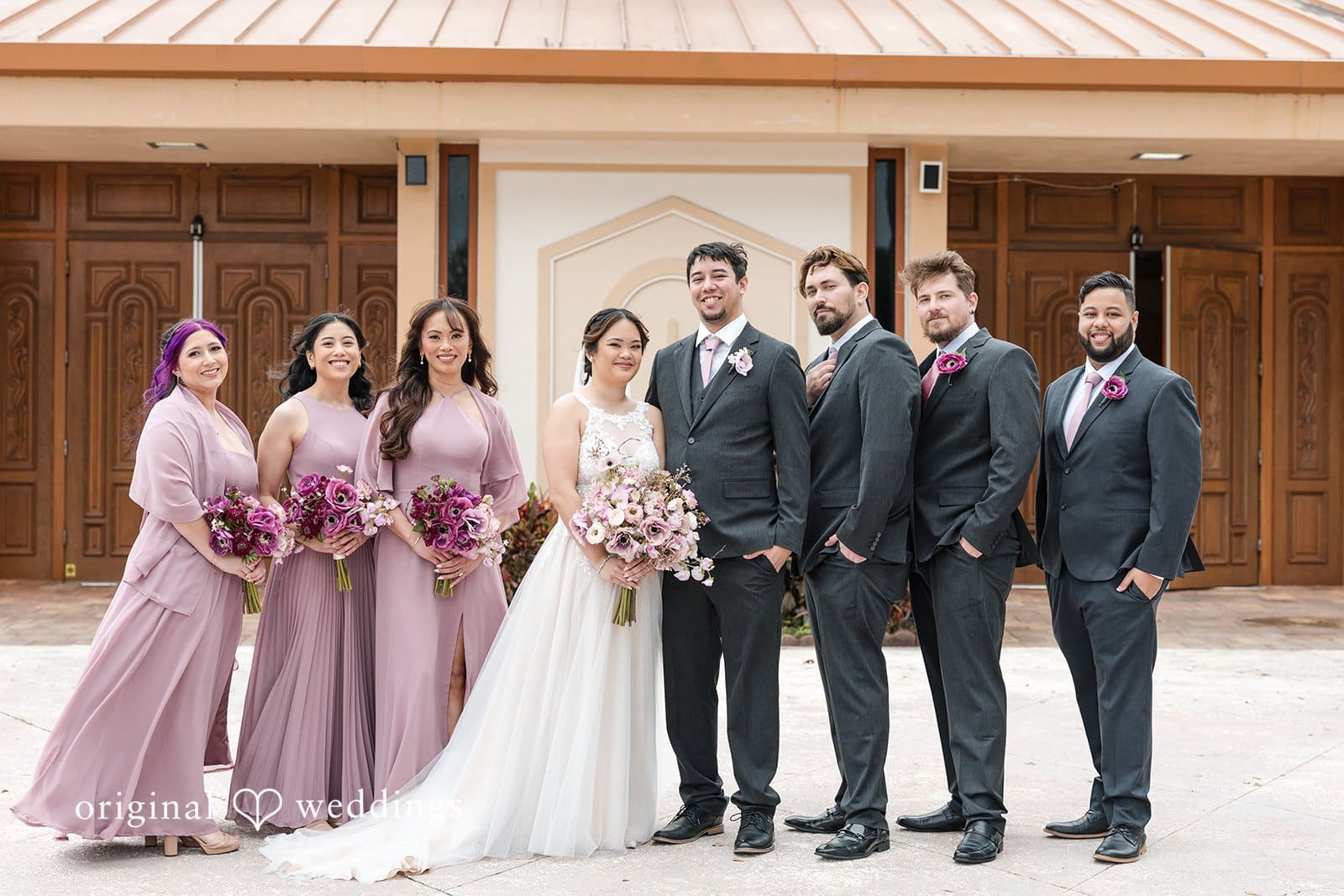 Wedding party with bride, groom, and bridesmaids in pink dresses.