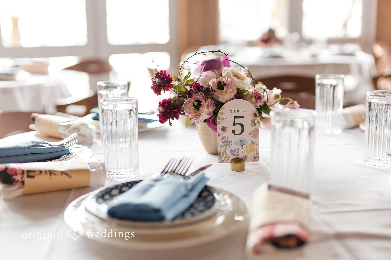 Wedding table set with floral centerpiece and table number.