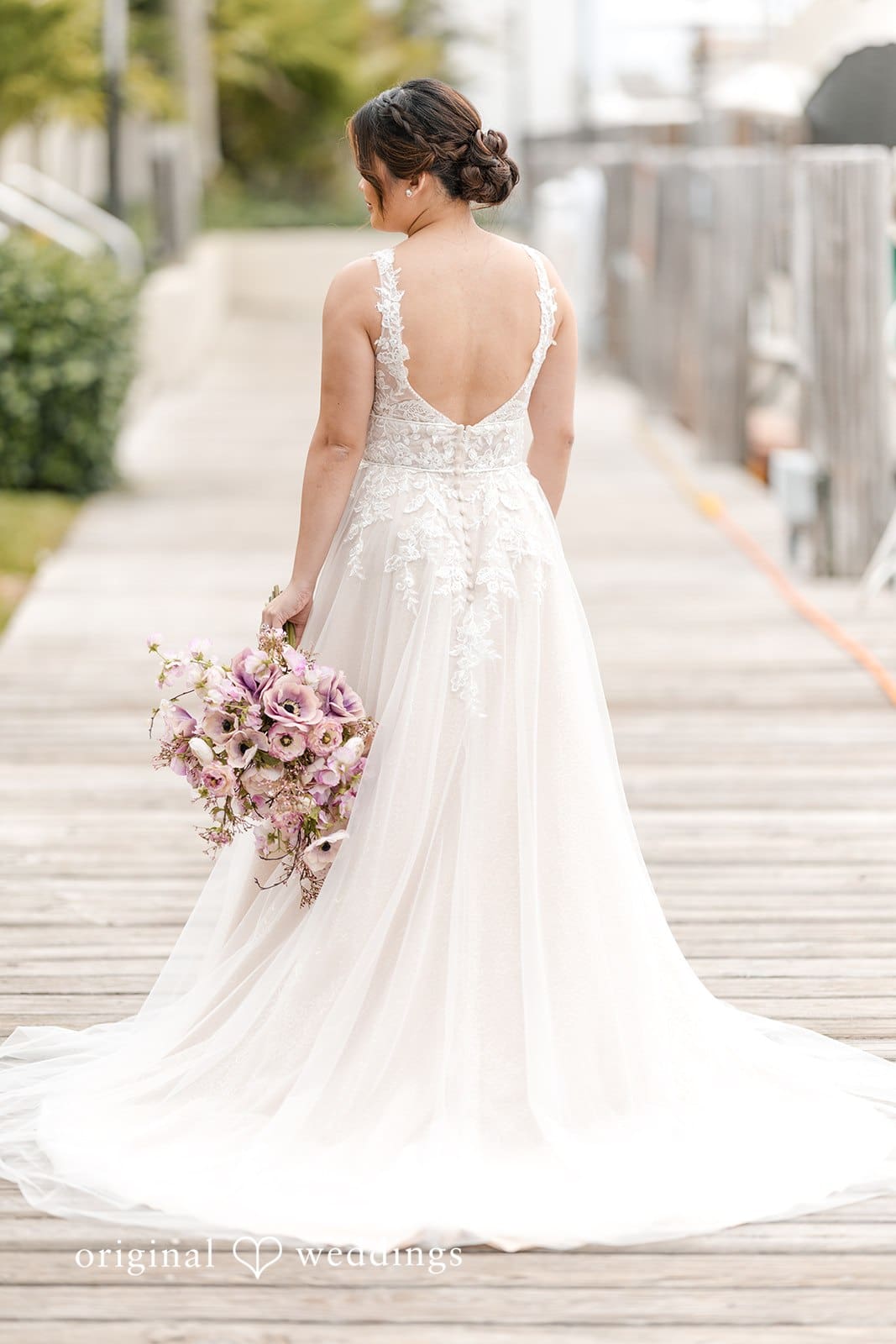 Bride walking outdoors with bouquet, back view.