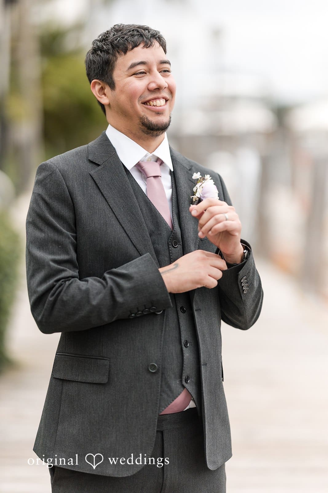 Groom adjusting his suit and smiling.