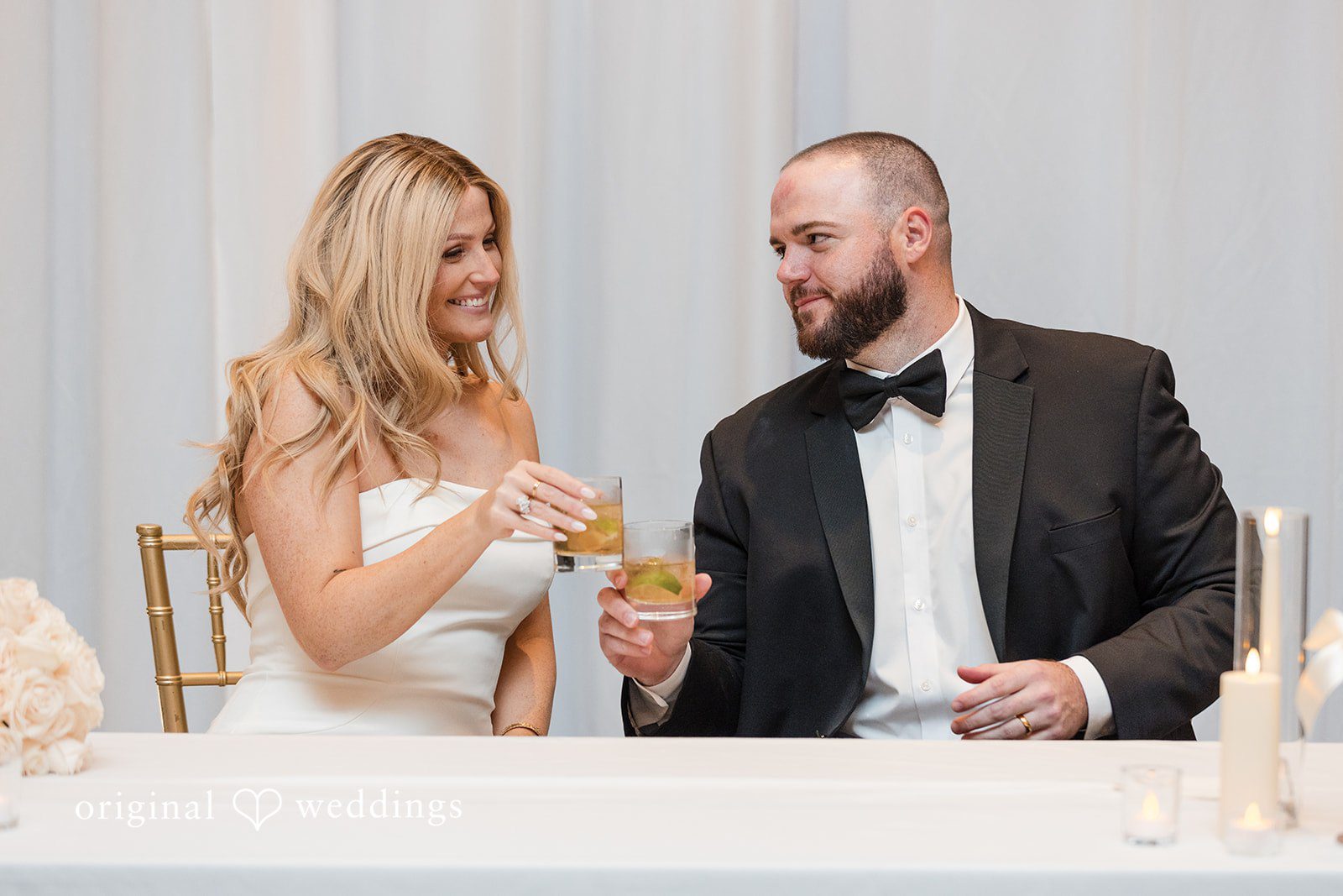 Bride and groom smiling while holding drinks.